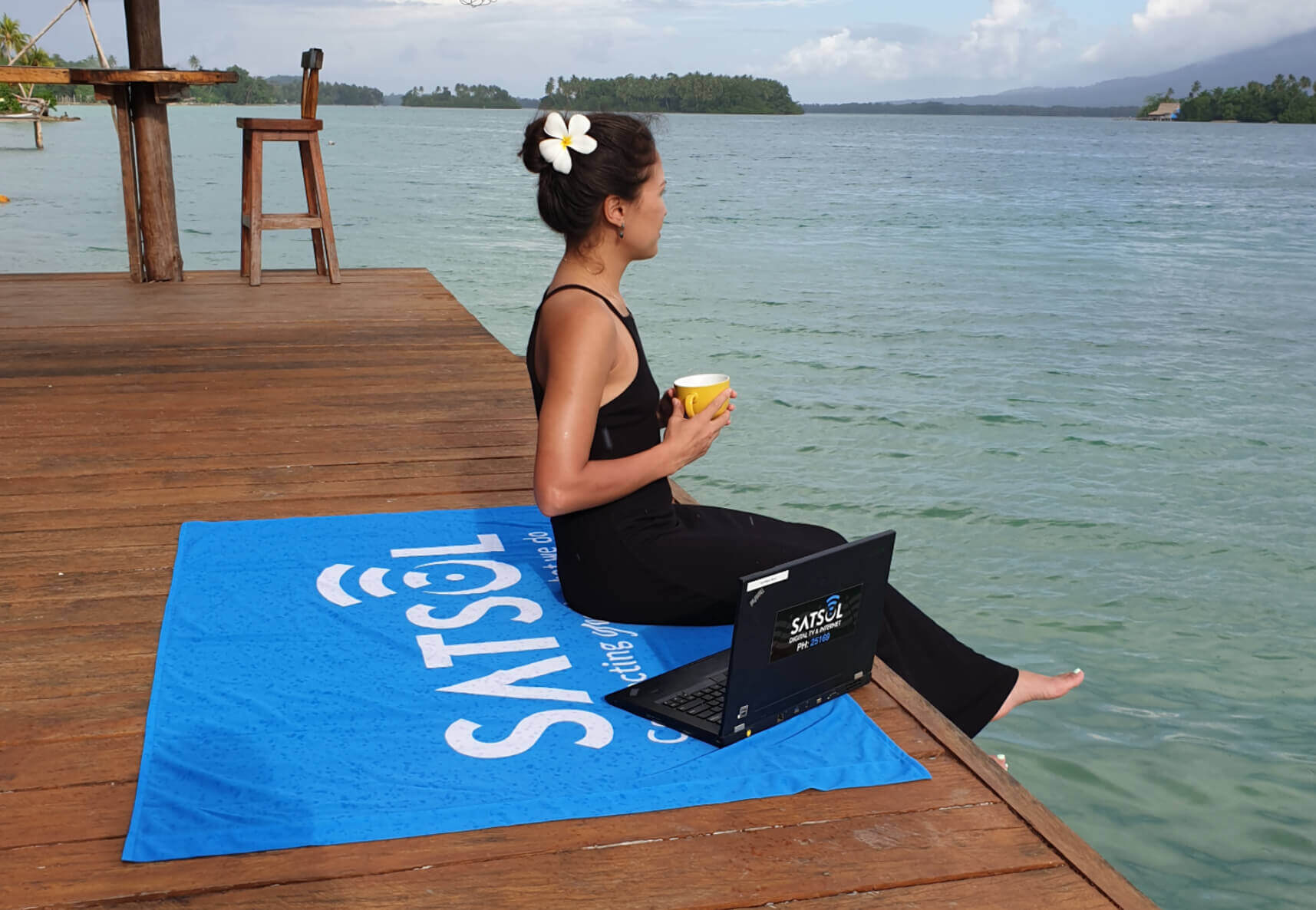 A woman sitting near a lake is connected to WI-FI with SATSOL hotspots